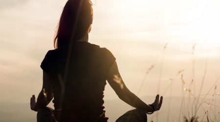 Silhouette of young woman practicing yoga outdoors